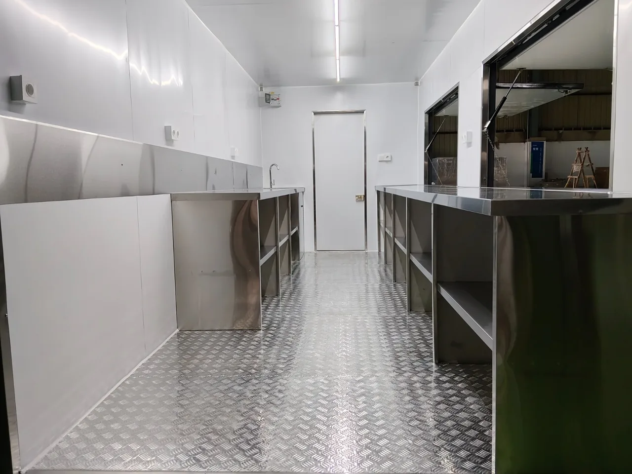 Vue en enfilade de l'intérieur du conteneur snack, plans de travail inox de chaque côté